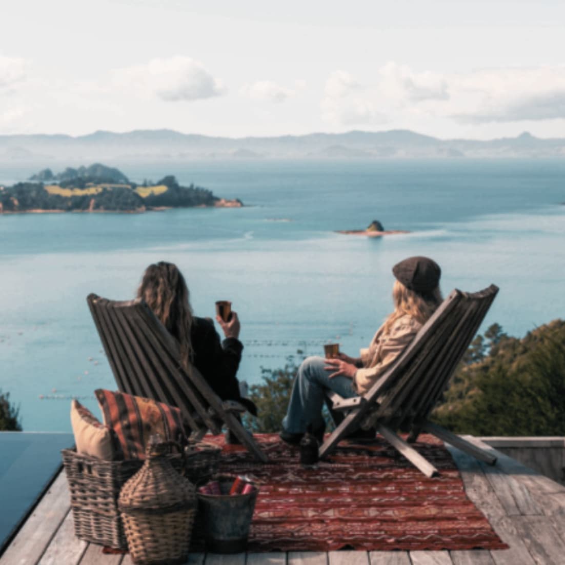 Two visitors relaxing on the deck overlooking the Hauraki Gulf